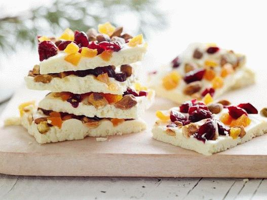 Foto Una tavoletta di cioccolato bianco con pistacchi interi, mirtilli rossi secchi e albicocche secche