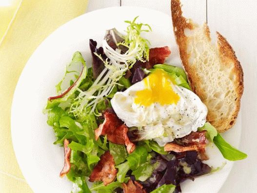 Insalata di foto con uovo in camicia e pancetta in un caffè