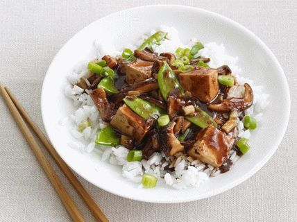 Foto di un soffritto con funghi shiitake, piselli e tofu