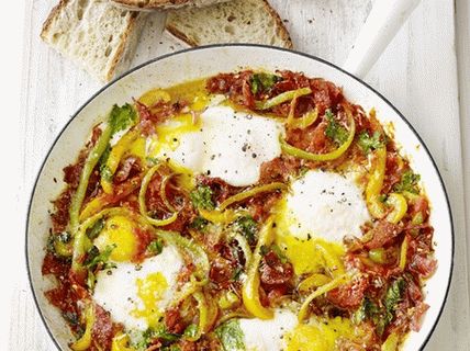 Foto Uova fritte in salsa di pomodoro con peperoni e salame